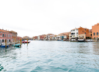 Scenic view of colorful Murano island buildings along the canal, showcasing traditional architecture and vibrant boats, perfect for travel enthusiasts and photographers