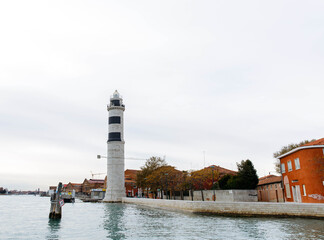 Murano, Italy - November 21, 2024: Lighthouse on the island of Murano stands tall against the...
