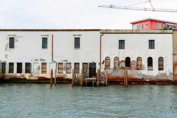 Murano, Italy - November 21, 2024: Historic buildings along the waterfront of Murano Island, showcasing weathered textures and vibrant colors, perfect for travel and architectural photography
