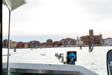 Murano, Italy - November 21, 2024: Scenic view from a boat approaching Murano Island, showcasing colorful buildings and historic architecture along the waterfront, perfect for travel enthusiasts