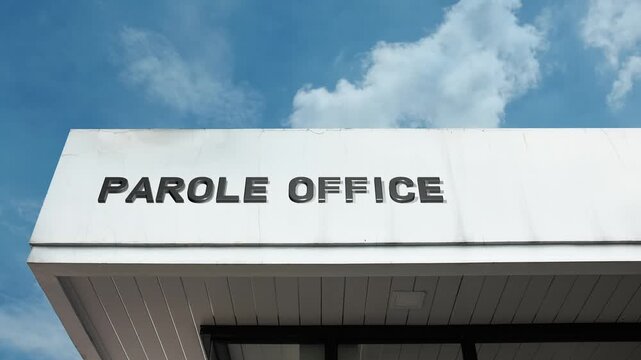 A Parole Office word sign displayed on a government or legal building under a clear blue sky, symbolizing judicial oversight, rehabilitation, probation, and law enforcement