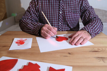 Person hand painting red heart shape for handmade craft