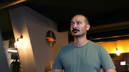 Front view of a man with a mustache walking on a treadmill in slow motion. 4K footage (Version 2) of a man in his 30s doing a light cardio exercise or warm-up.