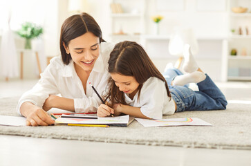 Portrait of a young happy smiling mother lying on floor with her teenage child daughter in casual...