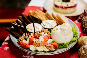 Burrata cheese with tomatoes, walnuts, and bread on festive holiday table