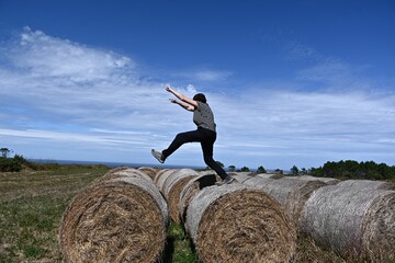 mujer saltando en los rollos de paja