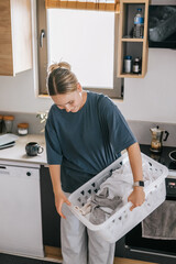 Laundry basket and coffee mug in a cozy home scene with a young woman in loungewear taking a break from housework; domestic life concept, candid indoor lifestyle background with copy space.