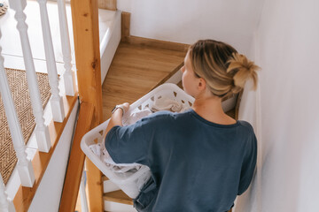 Laundry basket and coffee mug in a cozy home scene with a young woman in loungewear taking a break from housework; domestic life concept, candid indoor lifestyle background with copy space.