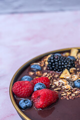 The morning dew still visible on the blueberries suggests immediate freshness alongside toasted cereal and slices of green kiwi.