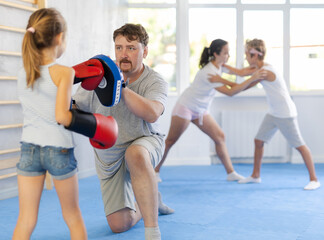 Fototapeta premium Father and daughter wearing boxing gloves practice boxing technique in gym