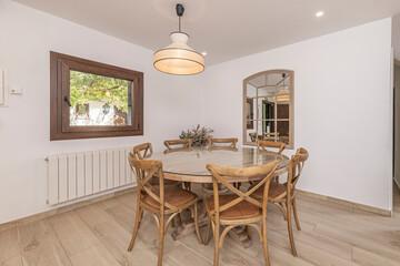 Dining set with a round mahogany table and Victorian chairs, with a bouquet of tea roses and aspidistra greens