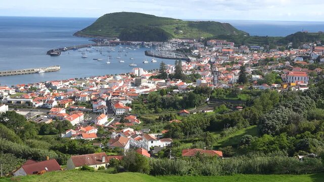 AZORES - 10.27.2025 - Fantastic aerial view of Horta's coastline on Faial Island, with buildings and small docked boats surrounded by greenery.