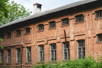 Old abandoned building with multiple rectangular windows, some with peeling paint and aged wooden frames. Part of weathered red brick wall with aged texture. Vntage architecture