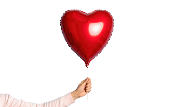 A hand holding a red, shiny heart-shaped balloon against a solid black background, symbolizing love and celebration