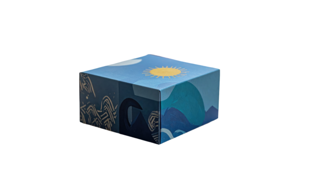 Cube-shaped box with a nature-themed design of sun, moon, mountains and ocean waves against a black background