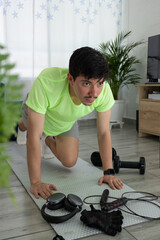 Man performing mountain climbers from a front angle on a mat in his living room. Home workout, cardio, energy, and healthy lifestyle