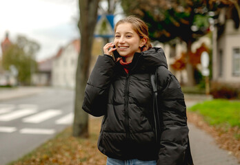 Fototapeta premium Happy Girl Talking On The Phone Against A Blurred Street Background