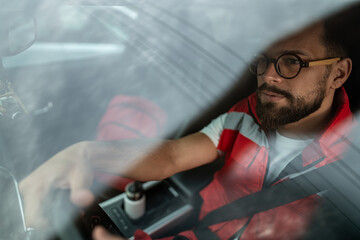 Male paramedic driving emergency vehicle responding to urgent call