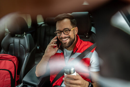 Paramedic man smiling talking on phone in car - Powered by Adobe
