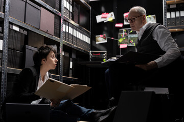 Private investigators team organizing confidential documents and case files, doing evidence...