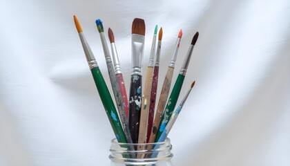 Collection of Assorted Paintbrushes in Glass Jar on White Background