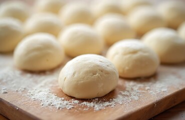 Raw yeast dough balls rest on wooden board dusted with flour. Preparing for baking bread, pizza or sweet buns. Unfinished pastry spheres ready for proofing. Domestic kitchen scene.