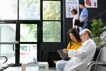 Woman practitioner interpreting test results on a health app, recovery steps with a patient indoors. Friendly experienced medic gives a thorough explanation and referrals for care.