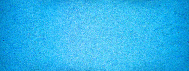 Blue paper background texture with gradient. Vintage cerulean cardboard backdrop with dark vignette border.
