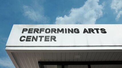 Performing Arts Center word sign displayed on a large cultural venue building under a clear blue sky, symbolizing live performance, theatre, music, and artistic expression