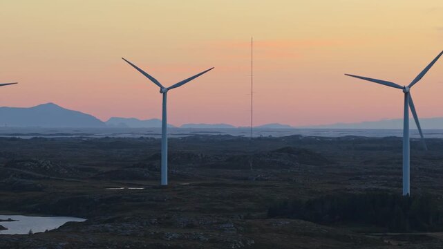 Norway wind towers cast shadows in golden hour, aerial scene