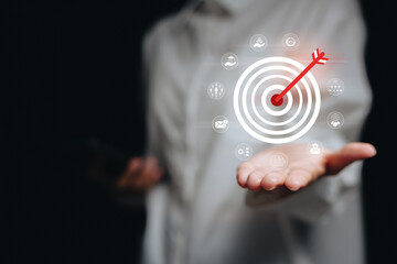 Target marketing concept. Business person using digital interface with arrow hitting bullseye to symbolize goal achievement, strategy, focus, and performance success in marketing.