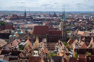 Fototapeta premium View from Nuremberg Castle, Germany, overlooking the city, with traditional timber-framed houses and the iconic towers of Sebalduskirche and St. Lorenz rising above the historic skyline.