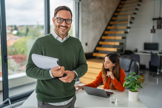Smiling businessman holding document folder in modern office