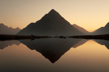 A majestic mountain reflected in a still lake at sunrise, symbolizing balance, clarity, and the serene power of achievement.