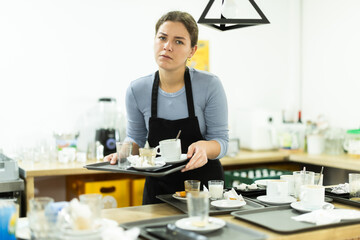 Fototapeta premium Cafe waitress carries a tray with dirty dishes