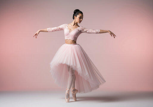 Elegant ballerina in pink tutu posing on pointe in a studio.