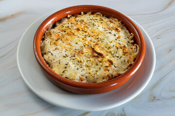 Creamy Kapsalon baked macaroni and cheese resting in ceramic ramekin with golden crust, sprinkled parsley, set on white plate over marble counter, warm homestyle comfort meal