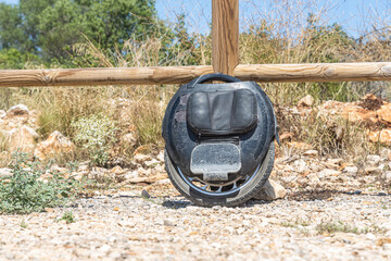 Electric unicycle leaning against wooden fence