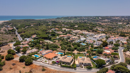 Obraz premium Aerial, Quarteira, Portugal Seaside community with vibrant colors, Coastal landscape featuring lively warm color palette, Beautiful shoreline view showcasing charming