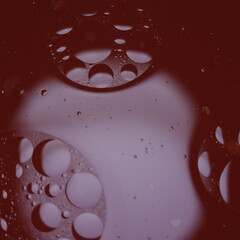 Una toma de cerca de un fondo abstracto de varias burbujas en agua y aceite en movimiento en un fondo de color  rojo, blanco y negro con algo de desenfoque