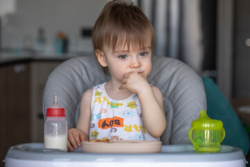 Infant girl eats deliciously while sitting at a childrens table
