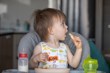 Infant girl eats deliciously while sitting at a childrens table