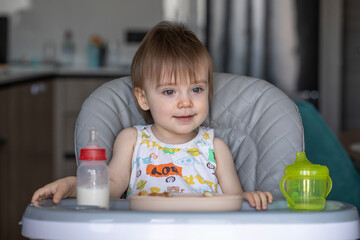 Infant girl eats deliciously while sitting at a childrens table