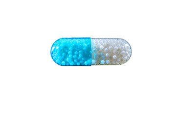 Close-up of a blue and white capsule pill filled with small spherical granules, isolated against a plain transparent background in a studio shot.