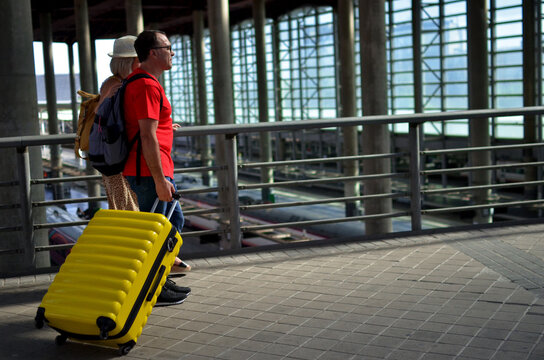 Couple traveling with yellow suitcase at train station