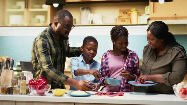 Happy cheerful parents teaching kids how to cook a homemade pizza, explaining steps and ingredients list and cooking together. Black family bonding during culinary education activity. Camera B.