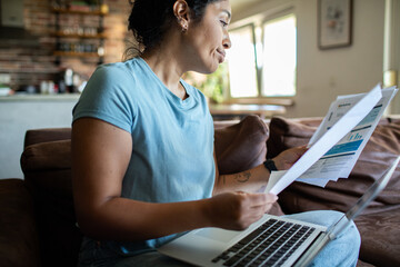Adult woman looking concerned while reviewing bills at home