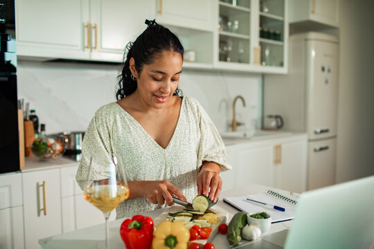 Adult woman smiling as she chops vegetables in home kitchen