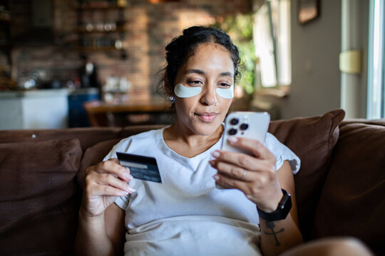 Adult woman focused on online shopping at home with eye patches