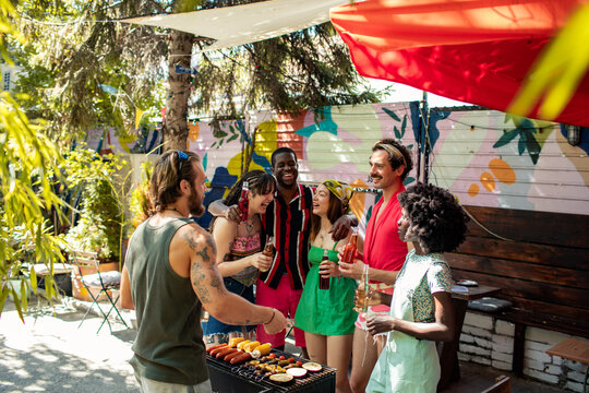 Young adult friends laughing at backyard barbecue party